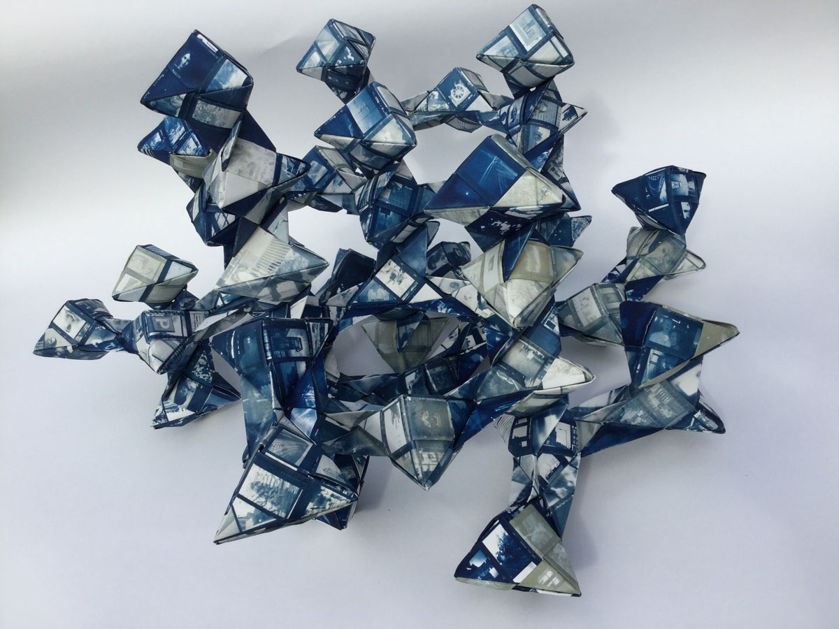 An origami sculpture of geometric forms coverd in cyanotype-printed autobiographical images