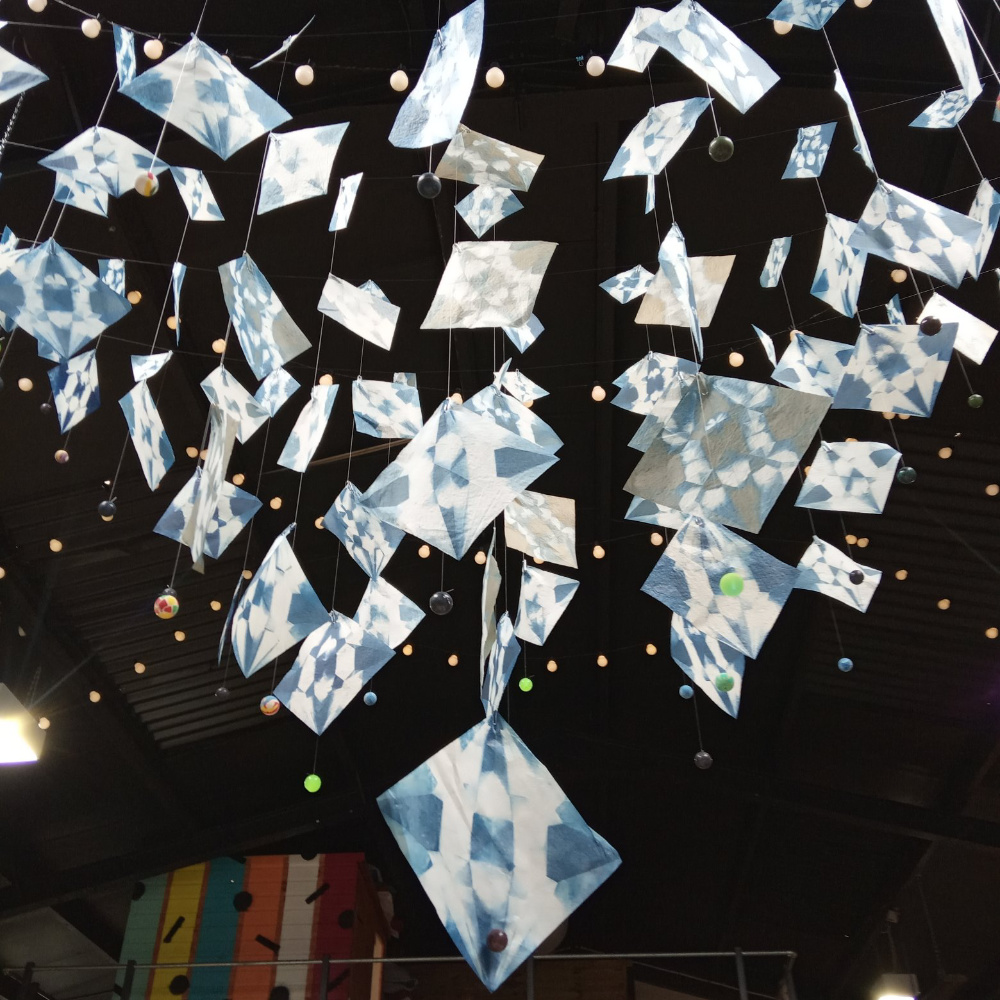a hung installation in the shape of an inverted pyramid, formed from dozens of cyanotype images on tissue paper